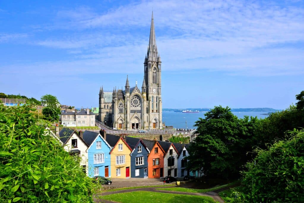 Casas coloridas com uma catedral imponente ao fundo na cidade portuária de Cobh, Condado de Cork, Irlanda.