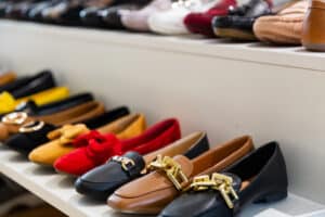 Sapatos do estilo mocassim, de diversas cores e modelos, enfileirados em uma prateleira. 