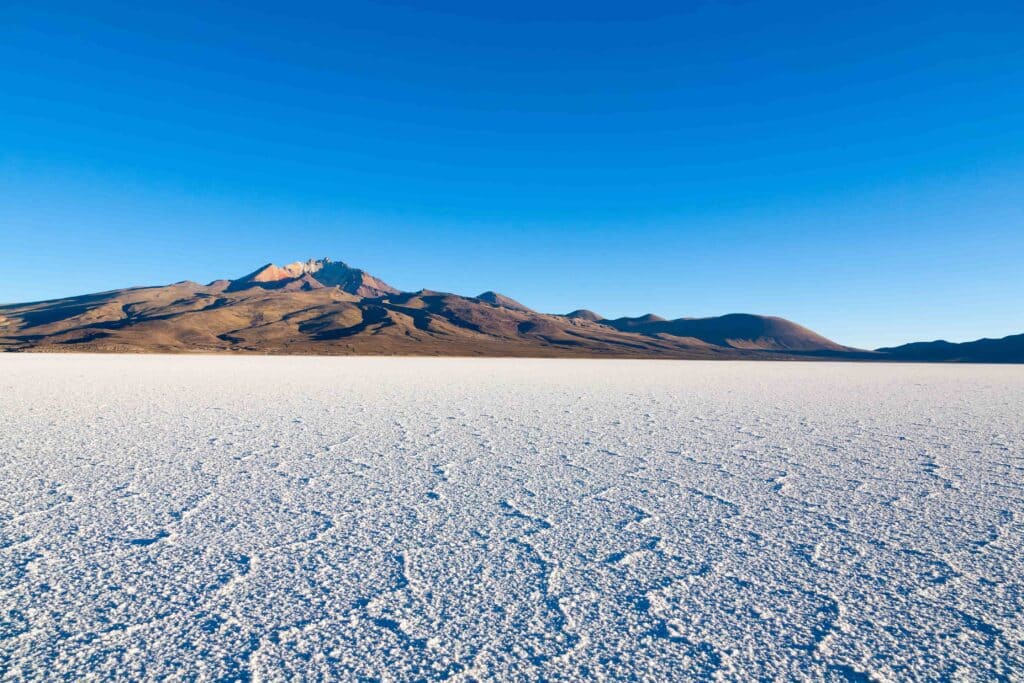 Vista terrestre do Salar de Uyuni com morro Cerro Tunupa ao fundo.