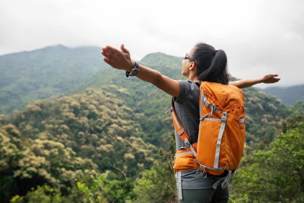 Mulher feliz torcendo por algo enquanto aprecia a vista no topo de uma montanha durante as primeiras horas da manhã.