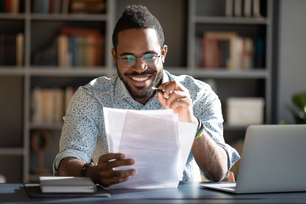 Homem negro sorrindo enquanto lê o seu planejamento financeiro.