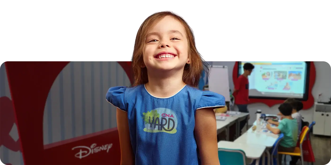 Criança entre 3 a 4 anos de idade sorrindo dentro de uma sala de aula CNA com temática Disney