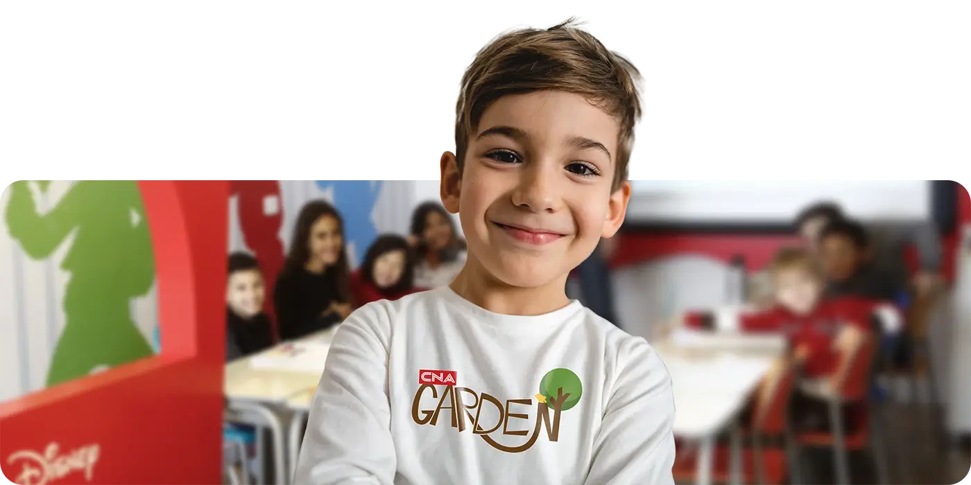 Criança entre 3 a 4 anos de idade sorrindo dentro de uma sala de aula CNA com temática Disney