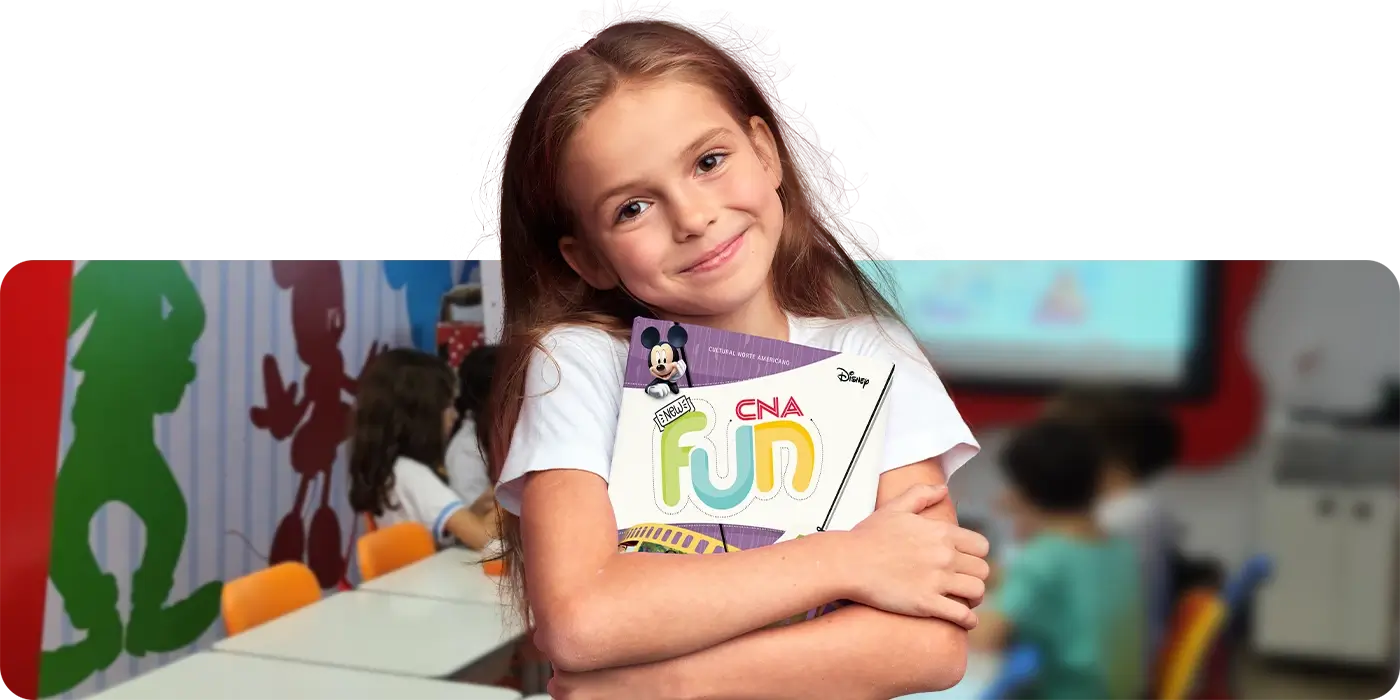 Criança entre 3 a 4 anos de idade sorrindo dentro de uma sala de aula CNA com temática Disney